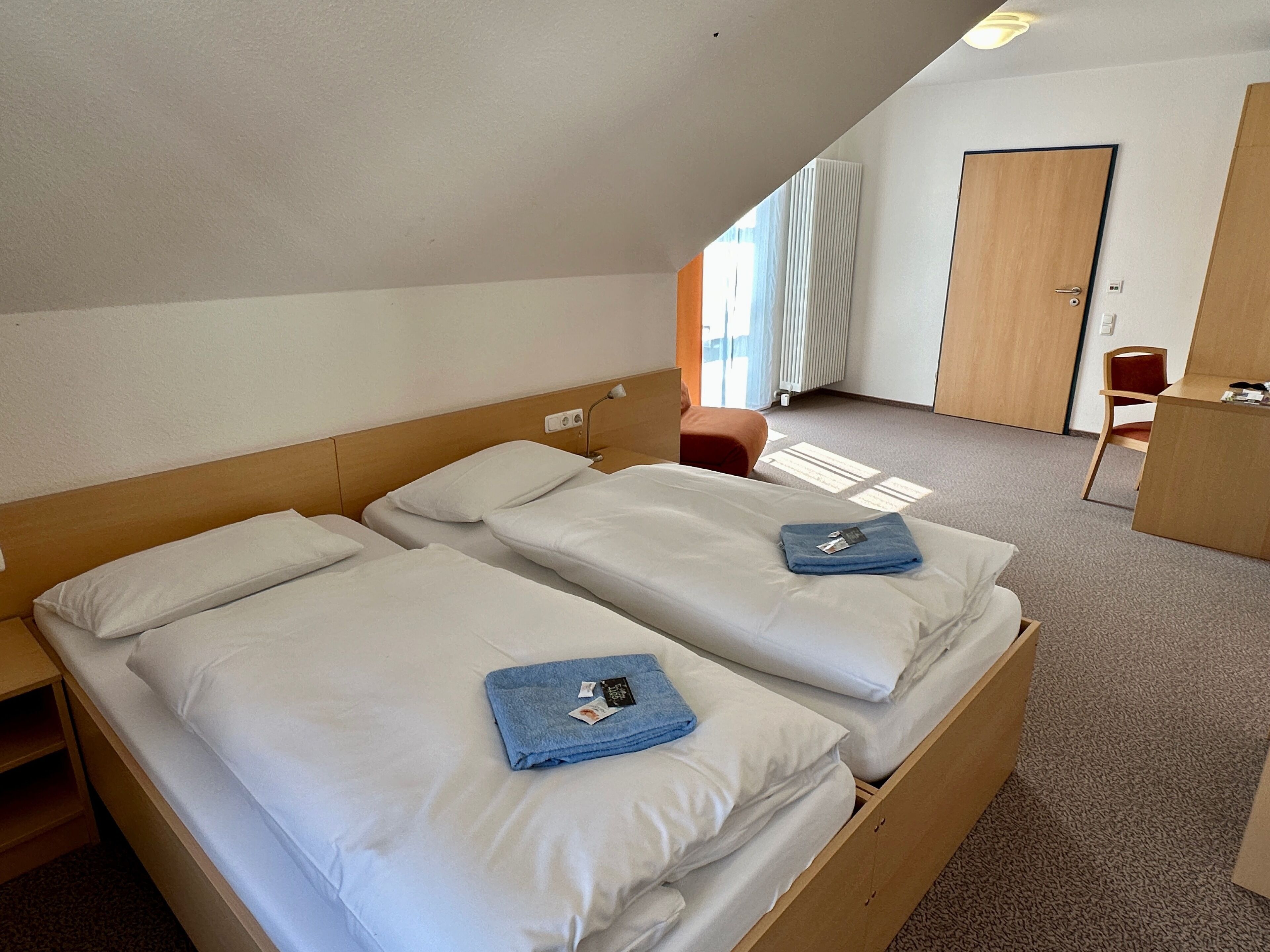 A hotel room with two beds, a desk, and a chair.