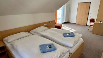 A hotel room with two beds, a desk, and a chair.