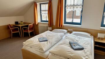 Quarto de hotel com duas camas, uma mesa e uma cadeira.