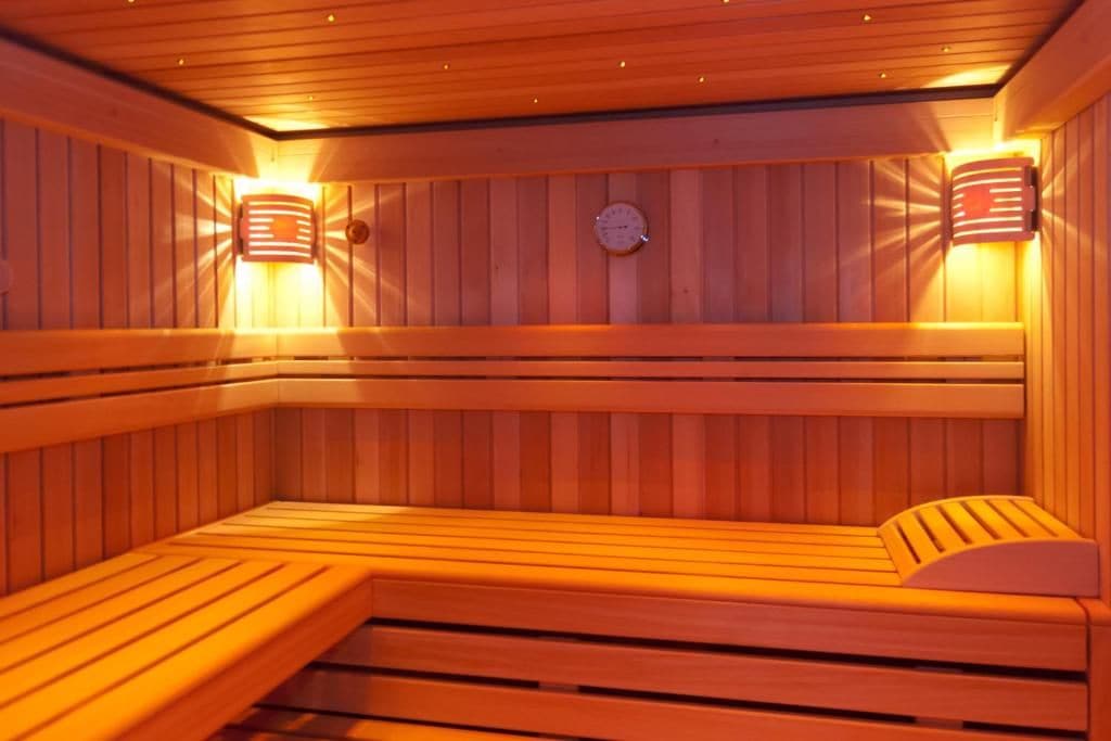 A sauna with wooden benches and wall-mounted lights.