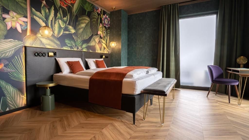 Ein modernes Hotelzimmer mit einem Bett, einem kleinen Tisch, einem Stuhl und einem großen Fenster.