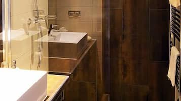Een moderne badkamer met een douchecabine van glas, een wastafel en een handdoekrek.