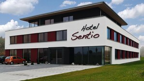 A modern hotel building with a flat roof, large windows, and a prominent sign reading "Hotel Sentio". - Hotel Sentio (Voehringen)