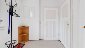 A hallway with a coat rack, a small wooden shelf with a bowl, and a door.