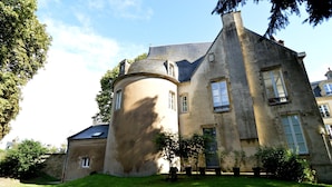 A large, historic building with a round tower, multiple windows, and a well-maintained lawn. - Cottage in Central Bayeux (Bayeux)