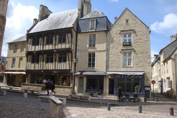 A historic building with a stone facade, a traditional timber-framed structure, and a restaurant named 'LE P'tit Resto' with outdoor seating.