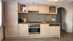 Cocina con armarios color beige, horno empotrado, pileta y una mesada con hervidor.