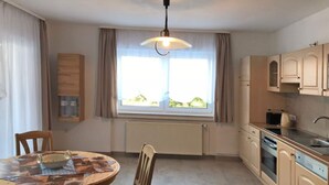 Una cocina compacta con comedor, una ventana con cortinas y un radiador.