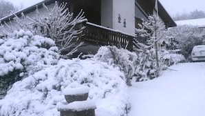 Una casa con un porche cubierto de nieve y una estatua.