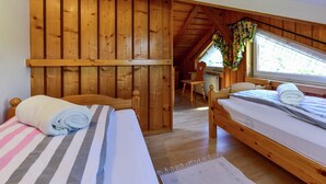 Una cabaña de madera con dos camas, una mesa de comedor de madera y una ventana con cortinas.