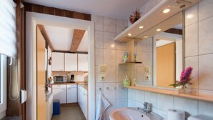 Un baño moderno con lavamanos, espejo y dispensador de papel higiénico.