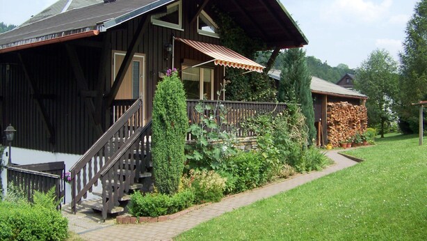 Una casa de madera con porche, escaleras y jardín.