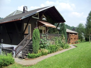 A wooden house with a porch, a staircase, and a garden. - Gemutliches Chalet in Rittersgrun in Waldnahe (Breitenbrunn/Erzgeb.)