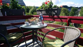 A balcony with a round table, two wicker chairs, and a potted plant.