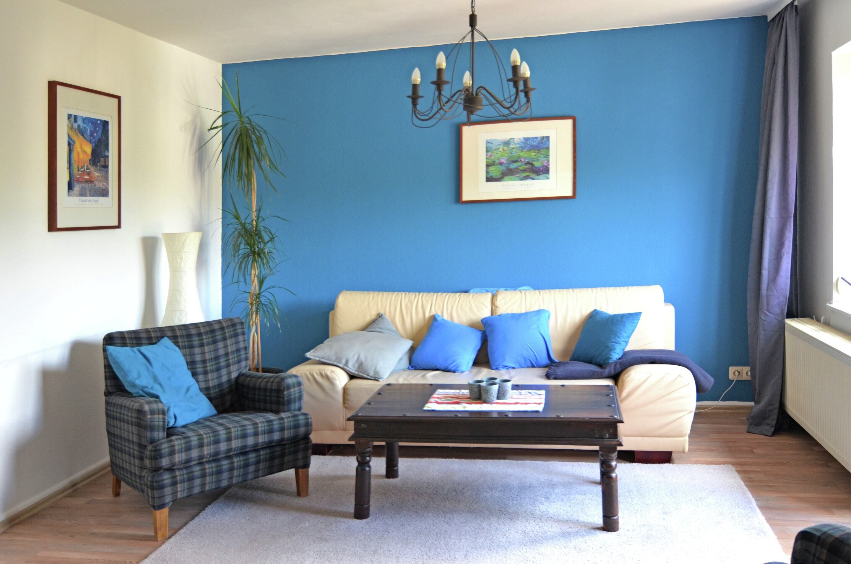 Een woonkamer met een bank, fauteuil, salontafel en een kroonluchter.