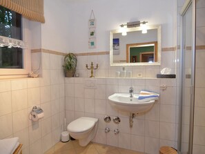 A bathroom with a toilet, sink, and shower. There is a mirror above the sink and a window with a curtain. - Aesthetic Apartment in Halblech Germany near Ski Area (Halblech)