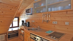 A compact kitchen with wooden walls, a microwave, a sink, and a Bosch dishwasher. - Quaint Farmhouse in Langenbach near Lake (Schleusegrund)