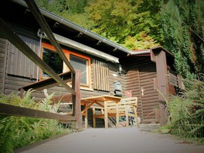 A rustic log cabin with a wooden deck and a table and chairs in front. - Holiday Home With Terrace (Stadlern)