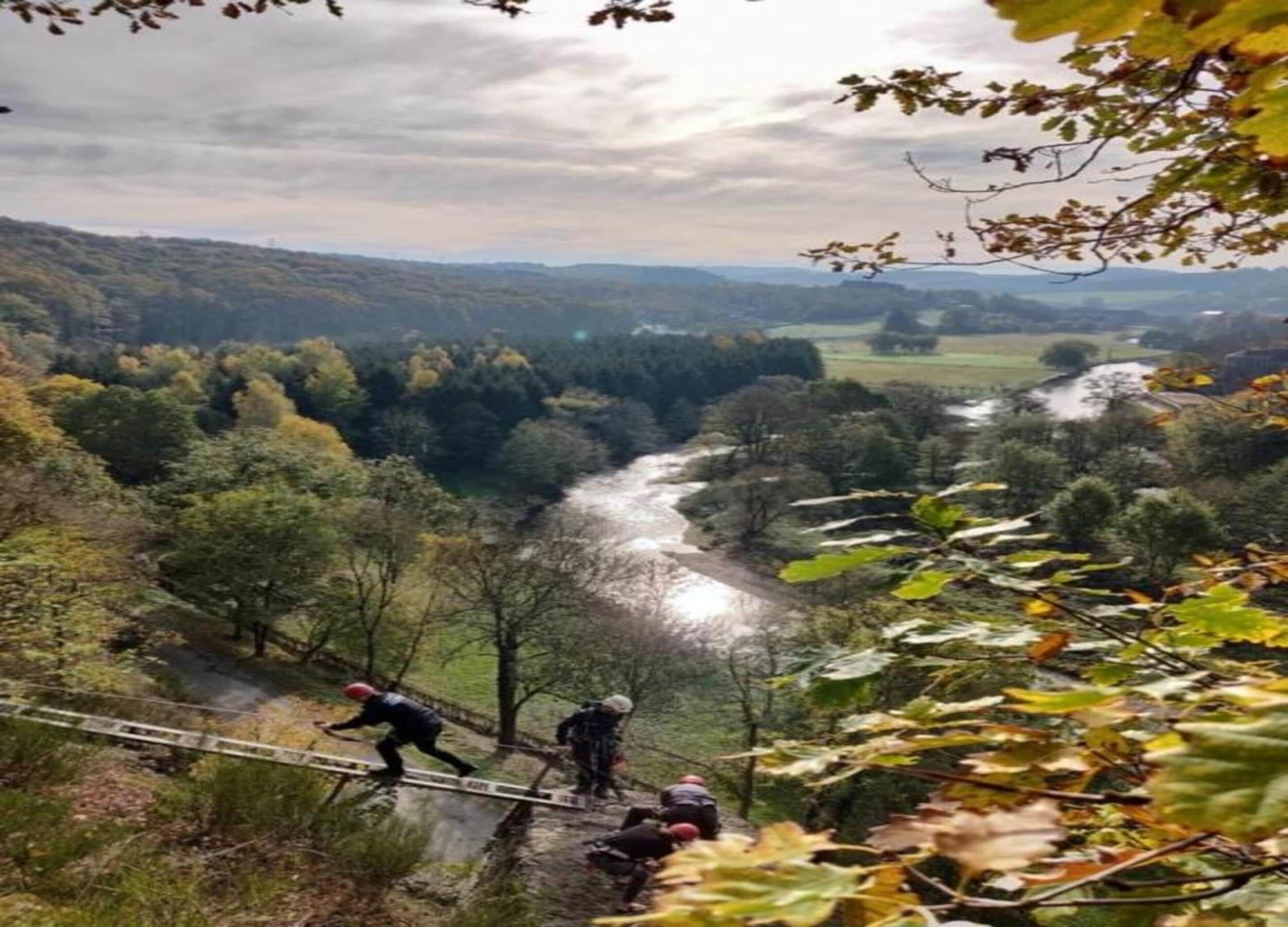 A scenic view of a river valley with a bridge and hikers.