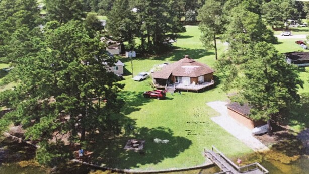 Una propiedad junto al lago con muelle, una casita con porche y una zona de césped.