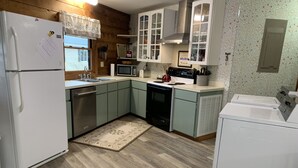 Una cocina equipada con refrigerador, microondas, estufa, lavaplatos y lavamanos.