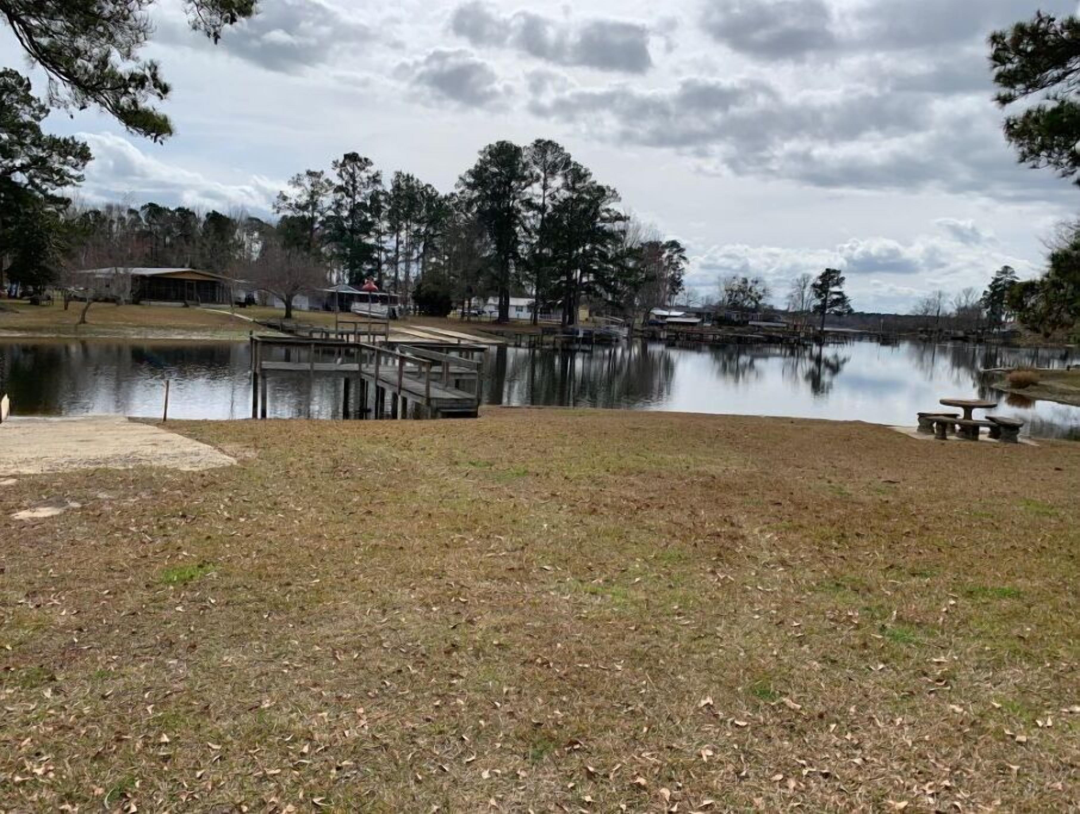 A lakeside park with a dock, picnic tables, and a grassy area.