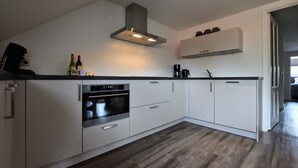 A modern kitchen with white cabinetry, a built-in oven, and a stainless steel range hood. - Apartment in Eibergen Near Zwillbrocker Venn (Eibergen)