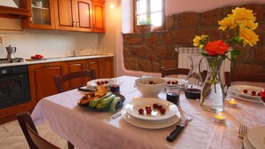 A dining area with a table set for two, featuring a variety of dishes, a vase with flowers, and a stone wall in the background. - Belvilla by Oyo Sorano (Sorano)
