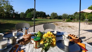 An outdoor dining setup with a table, chairs, and a view of a rural landscape. - Belvilla by Oyo Sorano (Sorano)