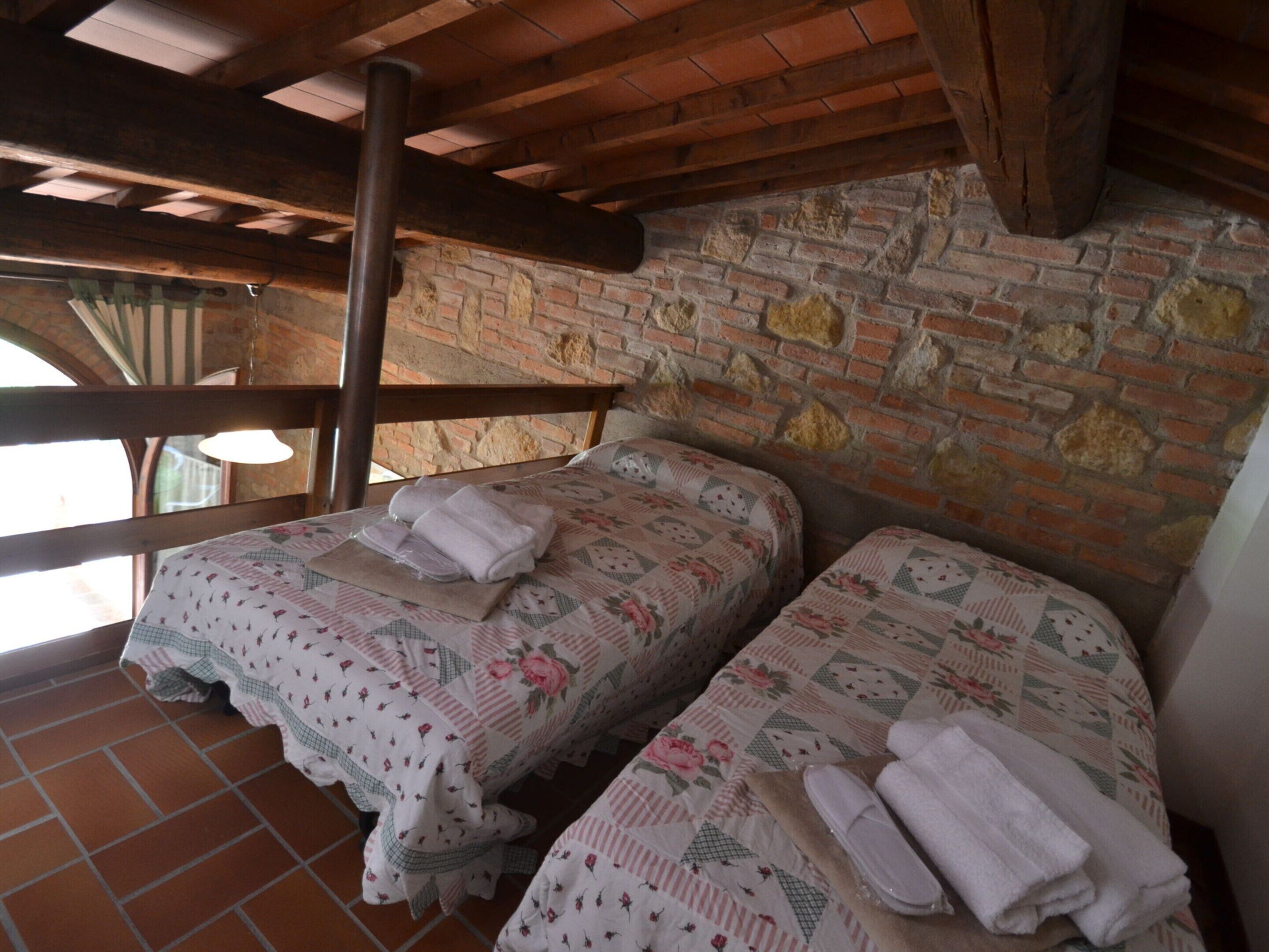 Une chambre rustique avec deux lits, un mur en briques et un plafond en bois.