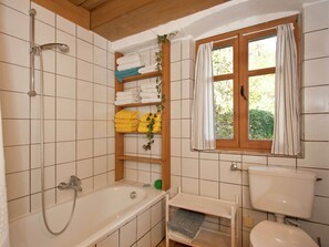 A bathroom with a bathtub, a shower, a toilet, and a window with curtains. - Superb Holiday Home in Weissenburg near Forest (Weissenburg in Bayern)