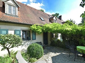 A house with a tiled roof, a small garden with a table and chairs, and a green door. - Superb Holiday Home in Weissenburg near Forest (Weissenburg in Bayern)