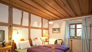 A wooden bed with a green mattress and purple bedding in a room with exposed beams and a window with curtains. - Superb Holiday Home in Weissenburg near Forest (Weissenburg in Bayern)