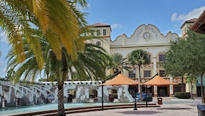 A courtyard with a fountain, palm trees, and a building with a sign reading "La Reina".