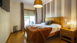 A bedroom with a bed, bedside table, lamp, and a view of the outdoors. - C15- The Patio de Convent Apartment (Lagos)