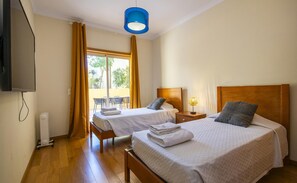 Une chambre d’hôtel avec deux lits, une télévision, un radiateur et une vue sur l’extérieur.