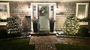 A house with a brick pathway leading to a door, two potted plants on either side, and a sign reading "STRACHAN". - Hingham Harbor Retreat ~ Sunsets ~ Family Gatherings ~ Trails at World’s End (Hingham,)