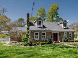 A two-story house with a brick exterior, a chimney, and a well-maintained lawn. - Hingham Harbor Retreat ~ Sunsets ~ Family Gatherings ~ Trails at World’s End (Hingham,)