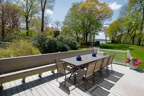 A wooden deck with a table and chairs, surrounded by greenery and trees. - Hingham Harbor Retreat ~ Sunsets ~ Family Gatherings ~ Trails at World’s End (Hingham,)