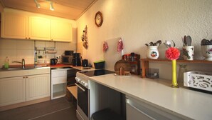 Eine Küche mit weißen Schränken, einem Herd, einem Backofen, einer Mikrowelle und einem Spülbecken.