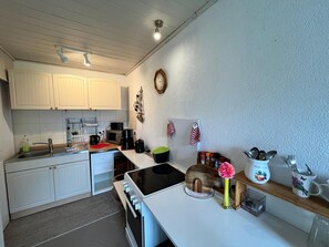 Eine Küche mit weißen Schränken, einer Mikrowelle, einem Herd und einem Spülbecken.
