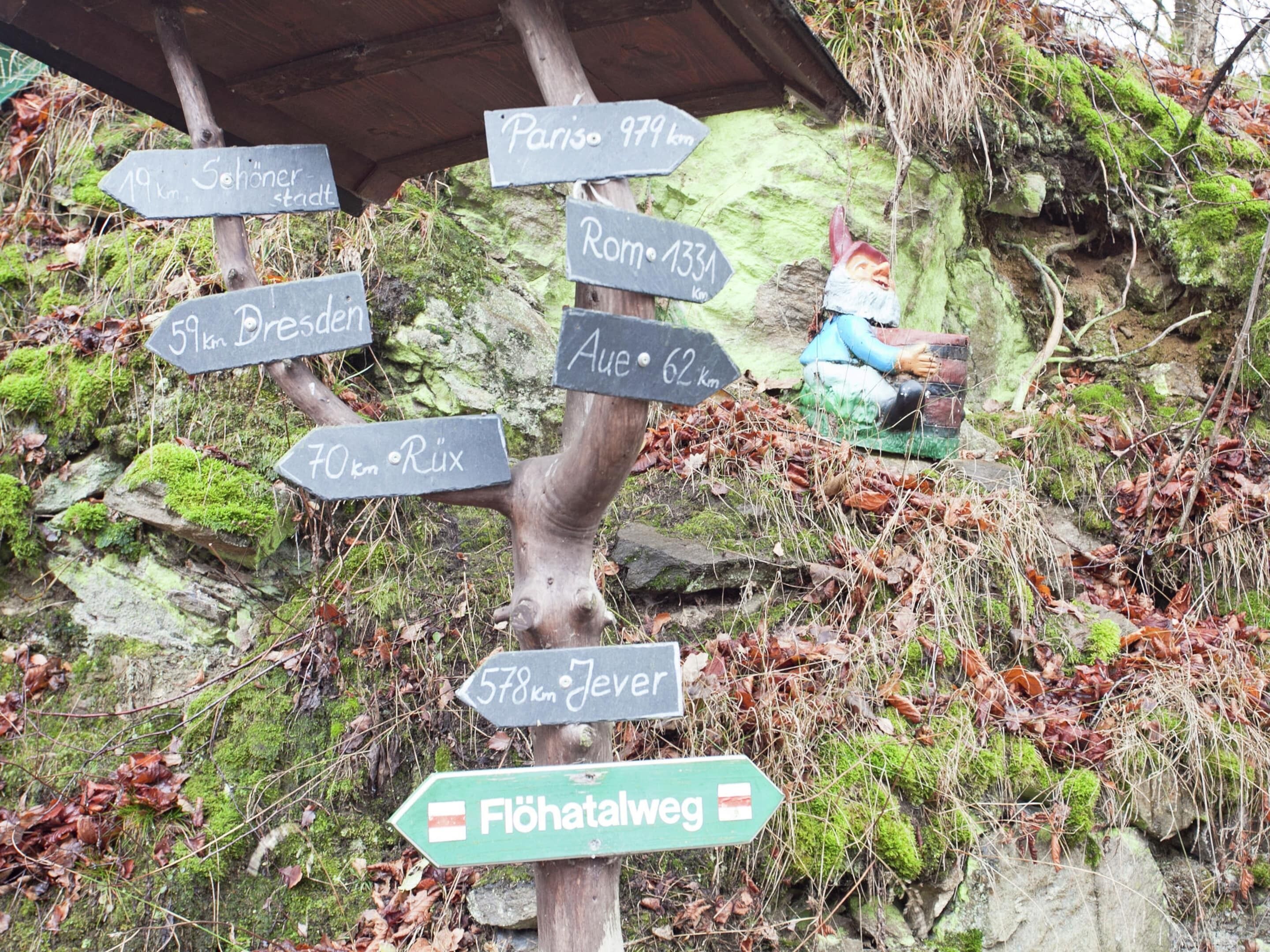 A wooden signpost with multiple directional signs indicating distances to various destinations.