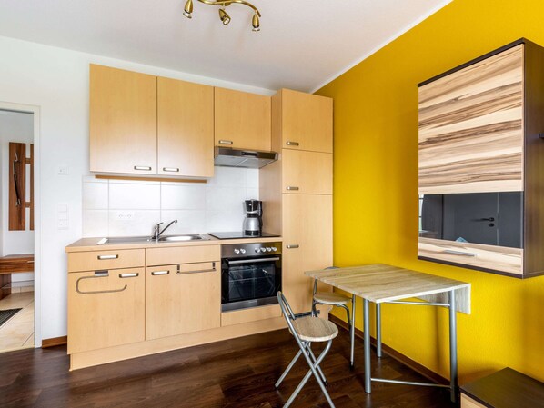 A modern kitchen with wooden cabinets, a built-in oven, and a coffee maker. - Ferienwohnung in der Nahe von Wismar (Wismar)