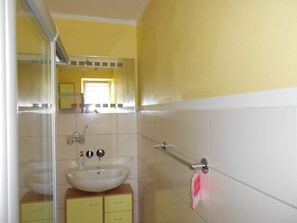 A bathroom with a yellow and white color scheme, a sink, a mirror, and a towel rack. - Spacious Apartment with Garden near Sea in Kröpelin (Kroepelin)