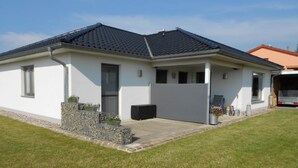 Une maison moderne de plain-pied, dotée d’un toit plat, d’une porte d’entrée et d’un petit porche.