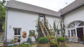 Un bâtiment blanc avec un toit en tuiles, un escalier en bois et une cour intérieure en briques.