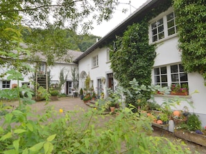 A white building with multiple windows and a garden area with potted plants and flowers. - Romantic Eifel Hideaway (Immerath)