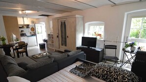 Un salon moderne comprenant un canapé, un téléviseur et un coin repas avec une table et des chaises.