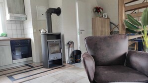 Een moderne keuken met een ingebouwde kookplaat, een eethoek met een bruine stoel, en een grote plant.