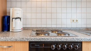 A kitchen with a stove, a coffee maker, and a water dispenser. - Ferienwohnung in Ediger (Ediger-Eller)